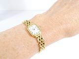 a woman ' s wrist that has a gold watch on it