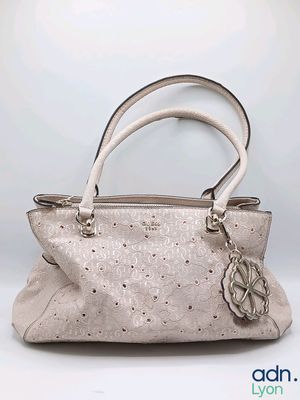 the handbag is made of leather and has a flower on the handle