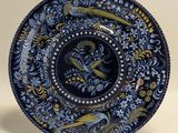 a close up of a blue and yellow plate with birds on it