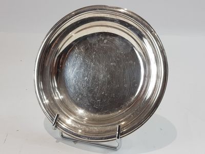 a silver plate on a stand on a white surface
