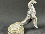 an old silver figurine of a dog sitting on top of a bowl