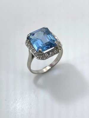 a close up of a ring with a blue stone surrounded by diamonds