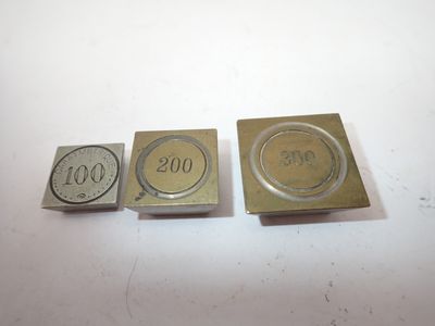 trois types différents d'estampes métalliques sur une surface blanche
