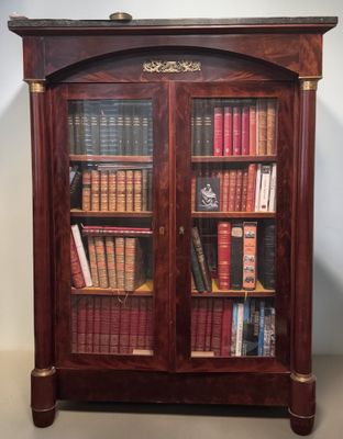 an antique bookcase with many books and a clock on top of it