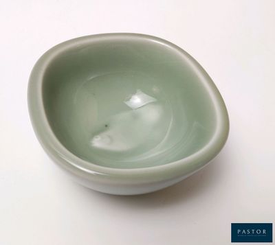 un petit bol vert posé sur une table blanche