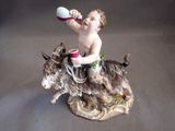 a figurine of a boy on a donkey drinking from a cup