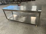 une table en acier inoxydable dans un entrepôt, avec plusieurs chaises à l'arrière-plan