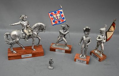 quatre figurines en argent représentant des soldats, posées sur des socles en bois et accompagnées d'un drapeau