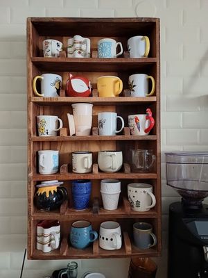 une étagère en bois sur laquelle sont posées de nombreuses tasses à café de différents modèles