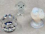 trois figurines en cristal posées les unes à côté des autres sur une table