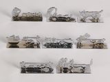 five silver metal animal figurines on display on a white surface