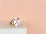 un gros plan d'une bague posée sur un socle, sur fond rose
