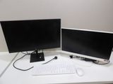 two computer monitors and a keyboard on a white desk