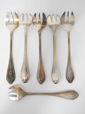 six forks and spoons are arranged in a row on a white surface