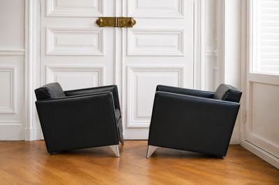 deux fauteuils en cuir noir placés devant une porte blanche
