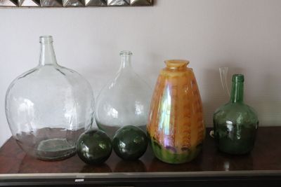 many glass vases on a table with a mirror in the background