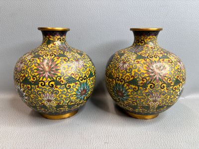 Deux vases sont posés sur une table, avec un mur blanc en arrière-plan.