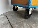 a blue cart that has a wooden box on it