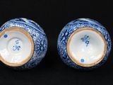 two blue and white vases sitting on a black surface