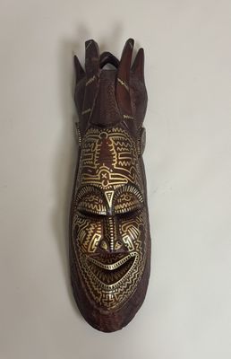 a close up of a wooden mask hanging on a wall