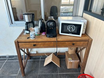 une table sur laquelle se trouvent un micro-ondes, une cafetière et d'autres objets