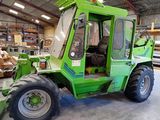 a green tractor parked inside of a building in a warehouse