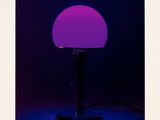 a purple lamp sitting on top of a table next to a black background