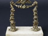une figurine ancienne en métal argenté représentant deux oiseaux, posée sur un socle en marbre