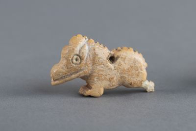 une petite figurine représentant un oiseau posée sur une surface grise
