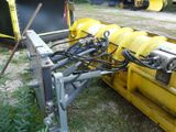 a yellow snow plow sitting in the grass