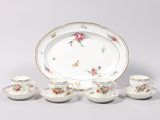 a white plate with flowers on it next to a cup and saucer