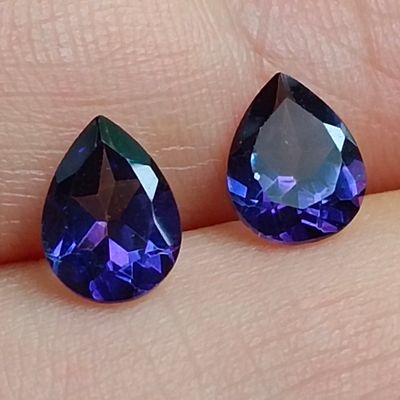 une paire de pierres précieuses bleues et violettes au doigt d'une personne