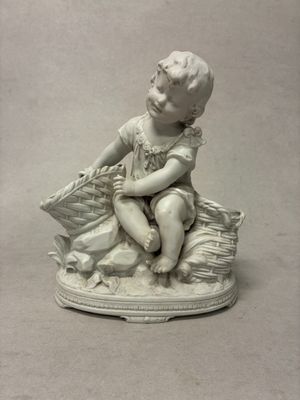 une petite statue représentant un garçon assis sur un oreiller