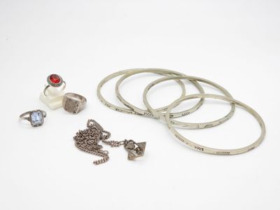 trois bagues, un bracelet et une bague ornée d'une pierre rouge sur un fond blanc