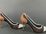 a pair of black and white high heeled shoes on a gray surface