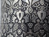 a close up of a metal vase with a pattern on it