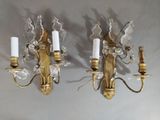 three brass and crystal sconces mounted on a white wall
