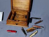 une petite boîte en bois contenant plusieurs types de couteaux