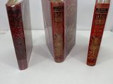 three red books sitting on top of a white table next to a piece of paper