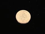 a close up of a gold coin on a black surface