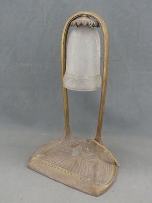 lampe de table en laiton et verre dépoli, posée sur un socle, sur fond gris