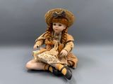doll sitting on the floor wearing a straw hat and dress