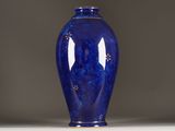 a blue vase sitting on a white table with a gray background