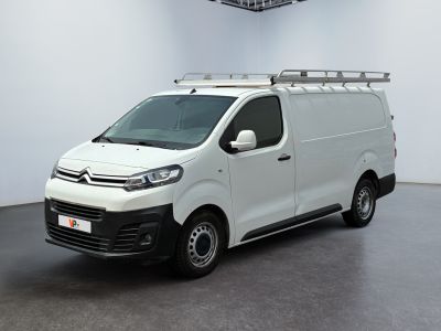 La camionnette blanche est garée dans une grande pièce équipée d'un ventilateur de plafond.