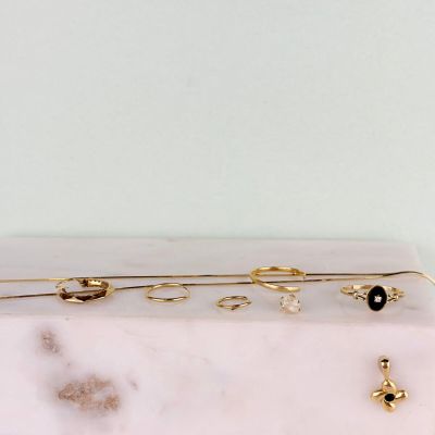 trois paires de boucles d'oreilles dorées et noires posées sur une plaque de marbre blanc