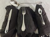 two forks and spoons sitting on a black napkin