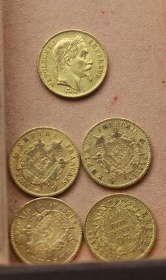 cinq pièces d'or posées dans une boîte sur une table