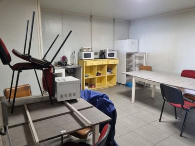 a room with a table, chairs, microwave, and a microwave oven
