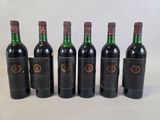 six bottles of wine are lined up in a row on a white surface