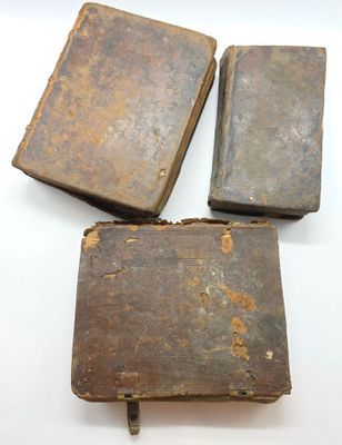 trois vieux livres sont posés sur une surface blanche